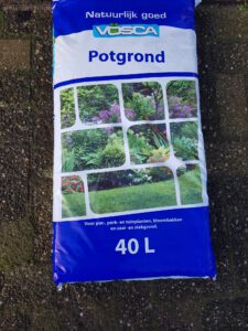 Een zak Rubens Tuinen professionele potgrond, specifiek samengesteld voor optimale plantgroei, weergegeven tegen een achtergrond van een groen ingerichte tuin in Capelle aan den IJssel.