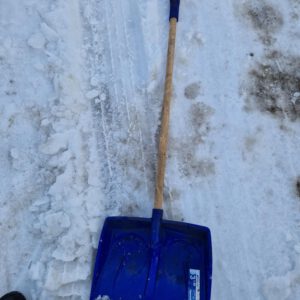 Lichtgewicht zwarte sneeuwschep met duurzame houten steel voor het ijsvrij maken van de oprit bij Rubens Tuinen.